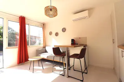 a living room with a table and chairs and a couch at LE FINOSELLO - T2 Cosy sur Ajaccio avec Clim, Wifi & Parking - proche Port & Aéroport in Ajaccio