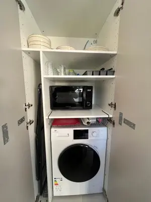 a small kitchen with a microwave and a stove at LE FINOSELLO - T2 Cosy sur Ajaccio avec Clim, Wifi & Parking - proche Port & Aéroport in Ajaccio