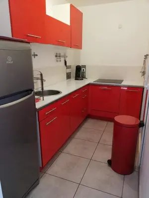 a kitchen with red cabinets and a red trash can at Studio calme proche de la gare de Borgo in Borgo