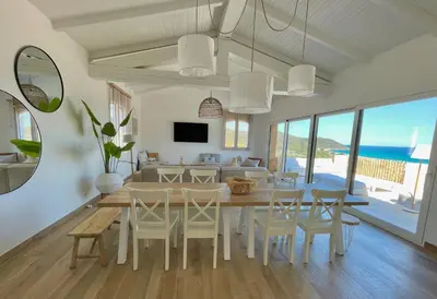 a dining room and living room with a table and chairs at Maison Bord'eau in Sainte-Lucie de Porto-Vecchio