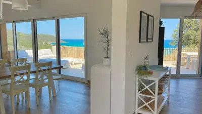 a dining room with a table and a view of the ocean at Maison Bord'eau in Sainte-Lucie de Porto-Vecchio