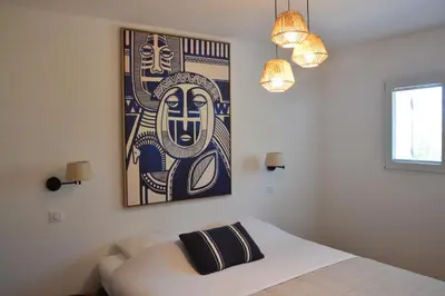 a bedroom with a bed and a painting on the wall at Maison Bord'eau in Sainte-Lucie de Porto-Vecchio