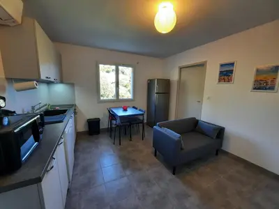 a kitchen with a couch and a table in it at F2 Alata proche d'Ajaccio rez-de-villa in Alata