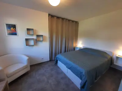 a bedroom with a bed and a chair and lights at F2 Alata proche d'Ajaccio rez-de-villa in Alata