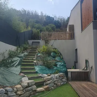 a garden with stairs and rocks next to a building at Duplex neuf T3 terrasse et jardin proche plages in Pietrosella