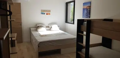 a small bedroom with a bed and a bunk bed at Duplex neuf T3 terrasse et jardin proche plages in Pietrosella