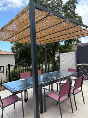 a table and chairs under a wooden umbrella on a patio at Villa neuve à 900 m de la plage in Santa-Lucia-di-Moriani