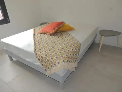 a bed with two pillows and a blanket on it at Villa neuve à 900 m de la plage in Santa-Lucia-di-Moriani