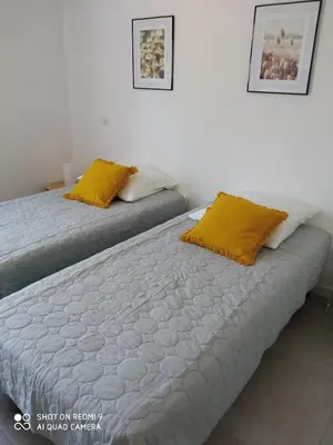 two beds with yellow pillows in a room at Villa neuve à 900 m de la plage in Santa-Lucia-di-Moriani