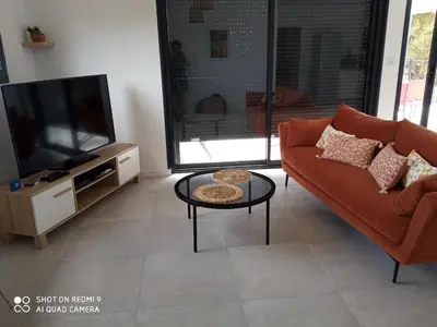 a living room with a couch and a tv at Villa neuve à 900 m de la plage in Santa-Lucia-di-Moriani