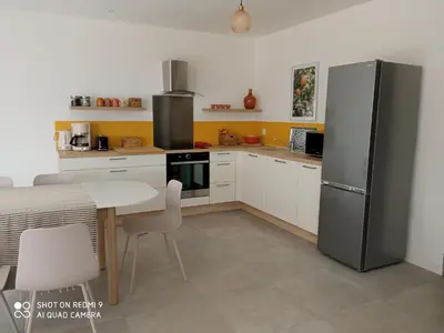 a kitchen with a refrigerator and a table with chairs at Villa neuve à 900 m de la plage in Santa-Lucia-di-Moriani
