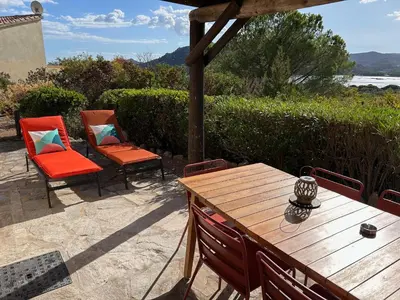 a wooden table and chairs on a patio at Villa vue mer exceptionnelle à 500m de la plage de Santa Giulia in Porto-Vecchio