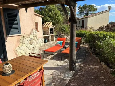 a patio with two chairs and a wooden table at Villa vue mer exceptionnelle à 500m de la plage de Santa Giulia in Porto-Vecchio