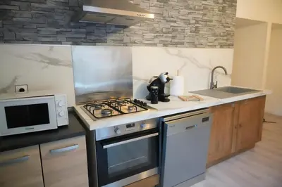 a kitchen with a stove top oven next to a microwave at Location F2 44 m2 in Venaco