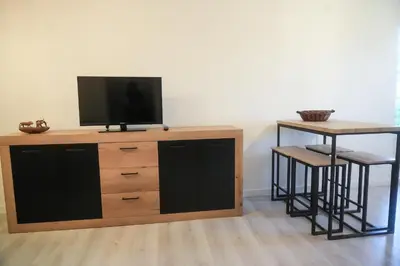 a tv on top of a wooden dresser with a table and stool at Location F2 44 m2 in Venaco