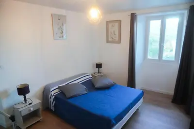 a bedroom with a blue bed and a window at Location F2 44 m2 in Venaco