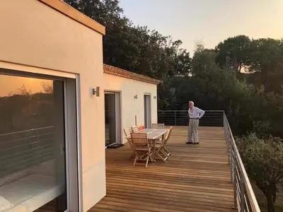 a man standing on the deck of a house at Villa en Corse du Sud - Golf d'Ajaccio in Coti-Chiavari