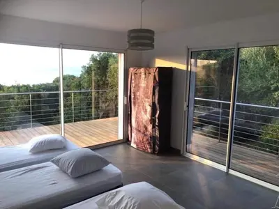 a bedroom with a bed and a balcony with sliding glass doors at Villa en Corse du Sud - Golf d'Ajaccio in Coti-Chiavari