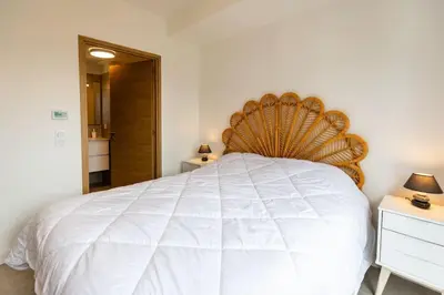 a bedroom with a large white bed with a wooden headboard at Appartement T3 Porto Vecchio in Porto-Vecchio