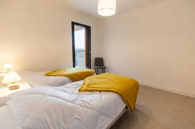 two beds with yellow sheets in a room with a window at Appartement T3 Porto Vecchio in Porto-Vecchio