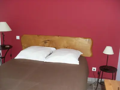 a bed with a wooden headboard and white pillows at Côté Lac Tolla in Tolla