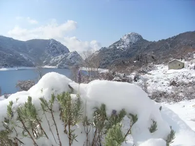 a snow covered field with a lake and mountains at Côté Lac Tolla in Tolla