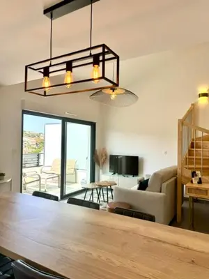 a living room with a large wooden table and a couch at Duplex en résidence in Propriano