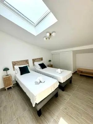 two beds in a room with a skylight at Duplex en résidence in Propriano