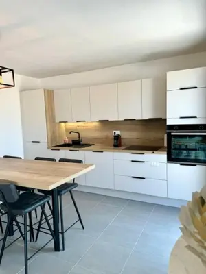 a kitchen with white cabinets and a wooden table at Duplex en résidence in Propriano