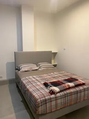 a bed with a plaid blanket and pillows on it at Charmant appartement hyper centre in Ajaccio