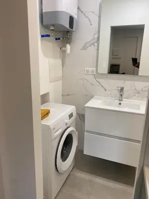 a white bathroom with a washing machine and a sink at Charmant appartement hyper centre in Ajaccio