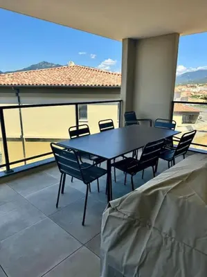 a table and chairs in a room with a large window at Magnifique appart T3 vue mer in Propriano