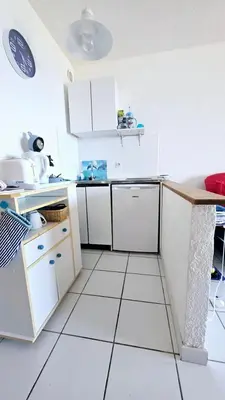 a kitchen with white cabinets and a white tile floor at Studio les pieds dans l'eau in San-Nicolao