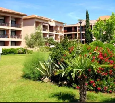 a large apartment building with a green yard with a plant at Studio les pieds dans l'eau in San-Nicolao