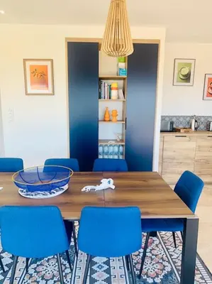 a dining room with a table and blue chairs at Villa vue mer et piscine privée in Sari Solenzara