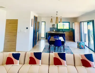 a living room with a couch and a dining room at Villa vue mer et piscine privée in Sari Solenzara