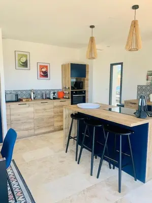 a kitchen with a large island with bar stools at Villa vue mer et piscine privée in Sari Solenzara