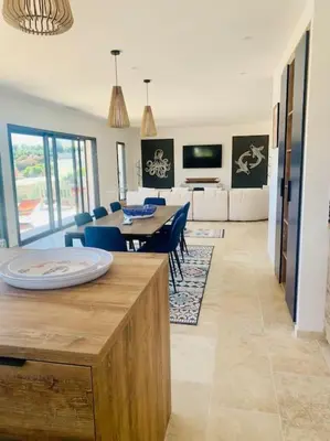 a dining room and living room with a table and chairs at Villa vue mer et piscine privée in Sari Solenzara