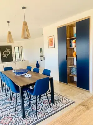 a dining room with a table and blue chairs at Villa vue mer et piscine privée in Sari Solenzara