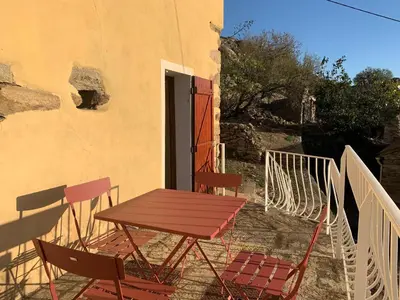 a wooden table and chairs on a balcony at Maison indépendante Haute-Corse mer et montagne in Santo-Pietro-di-Tenda