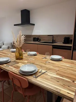 a wooden table with plates and glasses on it at Spacieux 3 chambres Centre-ville de Porto-Vecchio in Porto-Vecchio