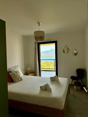 a bedroom with a bed and a large window at Appart tout équipé et vue sur la mer in Propriano