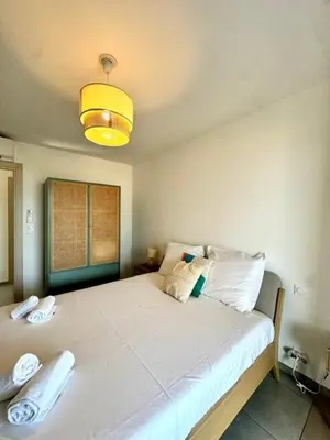 a bedroom with a large white bed with a light at Appart tout équipé et vue sur la mer in Propriano