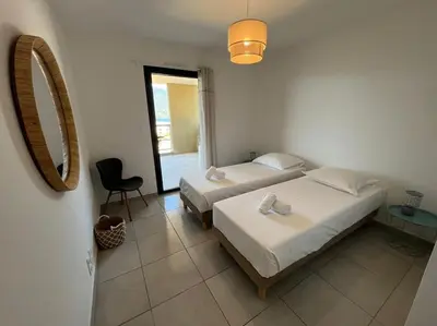 a bedroom with two beds and a mirror and a chair at Appart tout équipé et vue sur la mer in Propriano