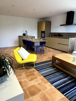 a living room with a yellow chair and a kitchen at Spacieux 2 chambres Centre-ville de Porto-Vecchio in Porto-Vecchio