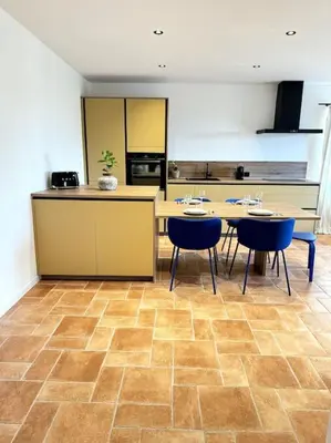 a kitchen with tables and blue chairs in a room at Spacieux 2 chambres Centre-ville de Porto-Vecchio in Porto-Vecchio