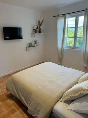 a white bedroom with a bed and a window at Spacieux 2 chambres Centre-ville de Porto-Vecchio in Porto-Vecchio