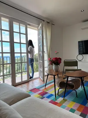 a woman looking out the window of a bedroom at Spacieux et lumineux 2 chambres vue mer Centre-ville de Porto-Vecchio in Porto-Vecchio