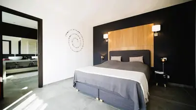 a bedroom with a large bed and a bathroom at Villa Suarticcia, 6 pers, piscine chauffée, 3 min plage en voiture in Sainte-Lucie de Porto-Vecchio