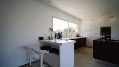 a kitchen with a white counter and two stools at Villa Suarticcia, 6 pers, piscine chauffée, 3 min plage en voiture in Sainte-Lucie de Porto-Vecchio